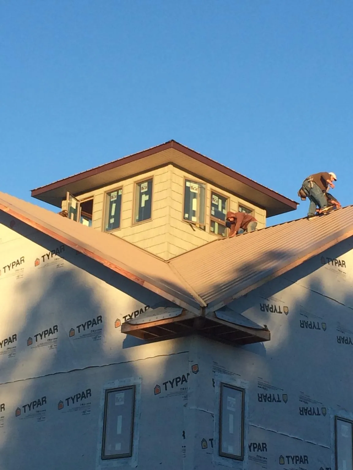 Roofers working around a rooftop cupola on a new metal roof at sunset — Roof Waterproofing in Montgomery by Roofing Brothers